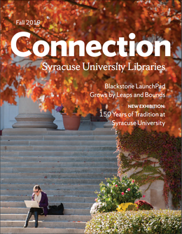 single student sitting on steps in front of Carnegie Library working on laptop; orange trees in foreground