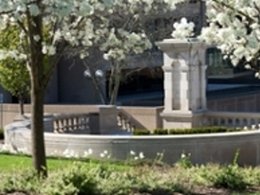 monument wall and column in outdoor area with flowers budding on trees