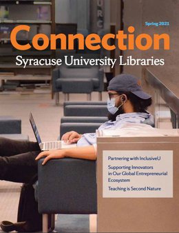 student wearing mask sitting in chair and working on laptop in library